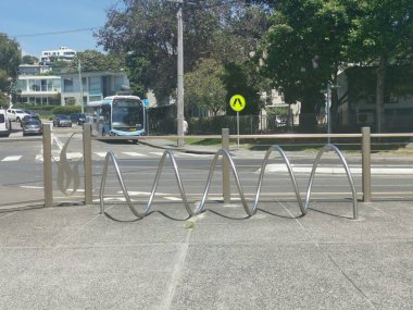 16 Kasım 2023 - Balmoral Beach, NSW, Avustralya: Arka planda otobüsle sokakta gümüş metal ortak bisiklet parkı