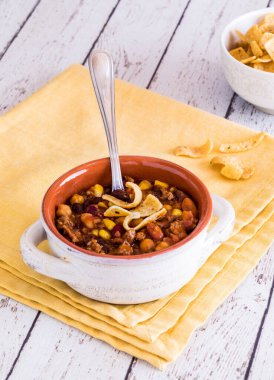 Ev yapımı kırmızı biberli mısır cipsiyle dolu bir çorba kasesini kapat.. 