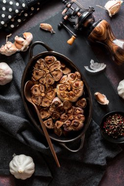 Fırından yeni çıkmış kavrulmuş sarımsak soğanlarının koyu bir arka planı var..