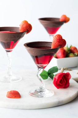 Elegant Valentines Day cocktails garnished with heart shaped strawberries, against a white background.