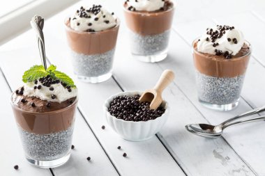 Healthy dark chocolate mousse chia pudding snacks against a bright window, ready for eating.