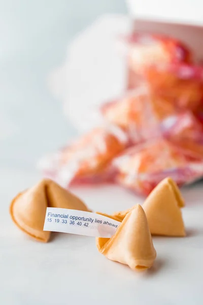 A close up of fortune cookies with a fortune sticking out of the one in front.
