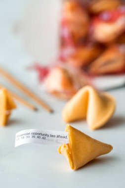 A close up of fortune cookies with a fortune note sticking out of the one in front. 