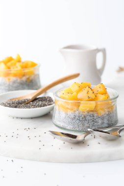 Close up of homemade chia pudding parfaits topped with chopped mango, ready for eating. 