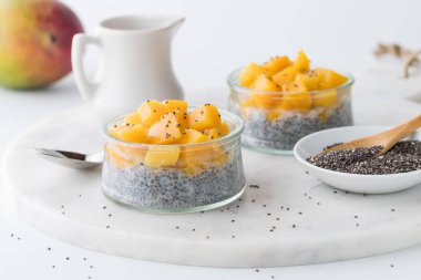 Delicious homemade chia pudding parfaits topped with chopped mango, ready for eating. 