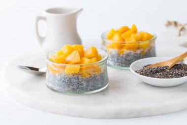 Close up of chia pudding parfaits topped with chopped mango pieces, ready for eating.