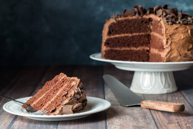 Üç katlı, düşük şekerli, bir dilim çikolatalı pasta, koyu bir arka planda..