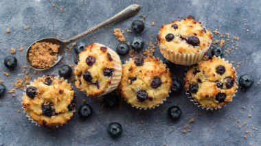 Top down view of an arrangement of freshly made blueberry muffins with sugar and blueberries.