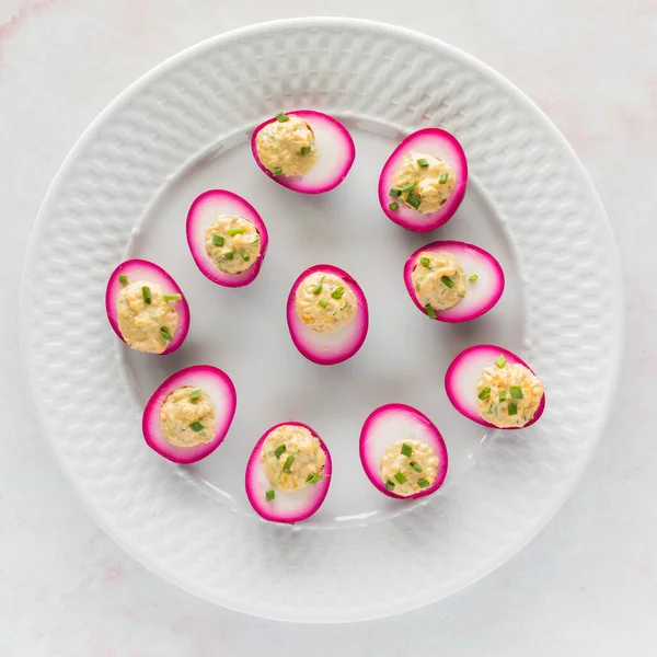 stock image Top down view of a plate filled with homemade beet juice soaked devilled eggs for Easter. 