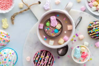 A look into a mug of hot cocoa with a hot chocolate bomb floating, surrounded by more hot cocoa bombs.