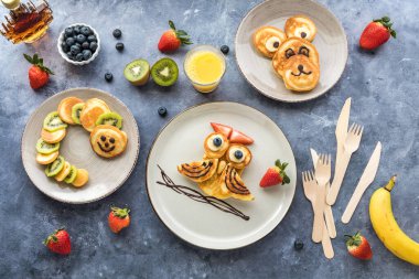Keto diet pancakes in the shape of different critters for kids, served with fruit and juice.