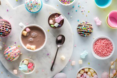 Above view of a mug of hot chocolate surrounded by hot cocoa bombs filled with sprinkles and marshmallows for Easter.
