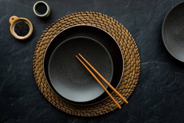 Çubuklar, soya sosu ve susam tohumlarıyla hasır bir masa örtüsü.. 