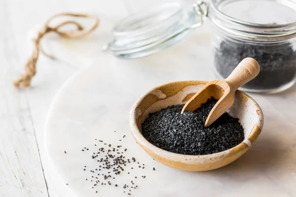 stock image A close up of black Hawaiian rock salt in a bowl with a small wooden scoop. 