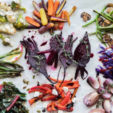 Parşömen kağıdında diğer renkli sebze gruplarıyla çevrili kızarmış pancarlar.. 