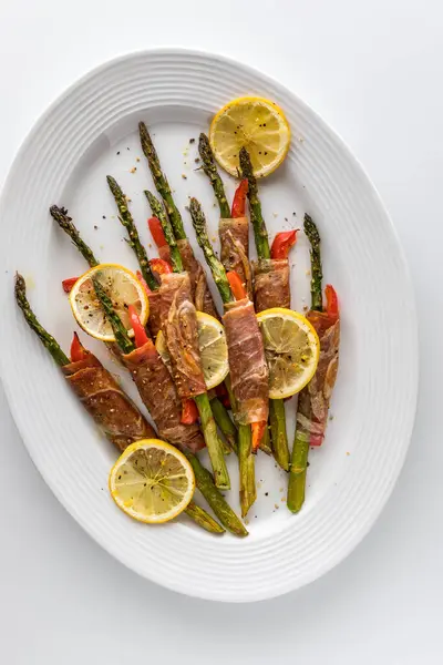 stock image Delicious roasted prosciutto asparagus and red pepper wrapped appetizers on a platter ready for eating. 