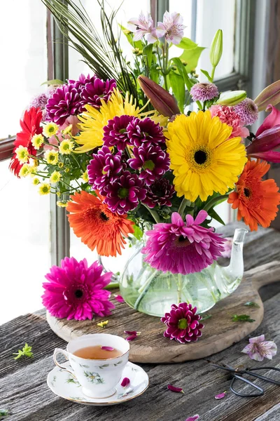 Ein Leuchtend Schönes Buntes Blumengesteck Mit Einer Tasse Tee Davor — Stockfoto