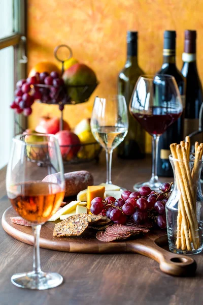 stock image An arrangement of Rose, white and red wine with a charcuterie board in the middle.