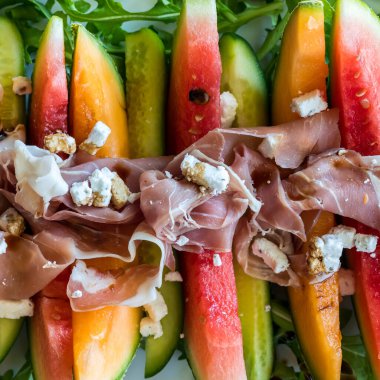 Üst aşağı kavun ve salatalık dilimleri Prosciutto ve peynir ile süslenmiş.. 