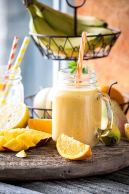 Taze meyvelerle çevrili sağlıklı bir mango turunçgil meyveli smoothie.. 