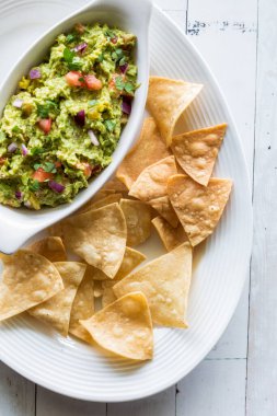 Bir tabak kızarmış tortilla cipsi. Yanında da ev yapımı avokado sosu.. 