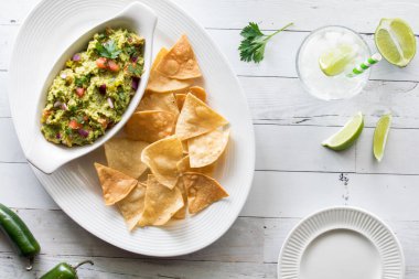 Ev yapımı avokado soslu çıtır tortilla cipsi, ferahlatıcı köpüklü su ve limonla servis ediliyor..