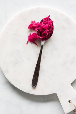 Sağlıklı pancar turşusu ve kırmızı lahana turşusu beyaz mermer bir levhada kaşıkta..