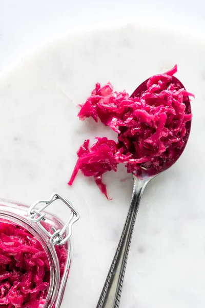 stock image Close up of pickled beet and red cabbage sauerkraut on a large spoon against a white background. 