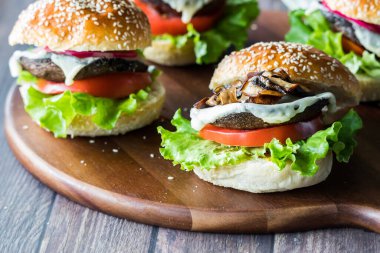 Tahta bir tahtanın üzerinde ev yapımı portobello mantarlı hamburgerler, yemek için hazır.. 