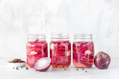 Kavanozlar dolusu ev yapımı kırmızı soğan turşusu, hafif arka planda biberli..