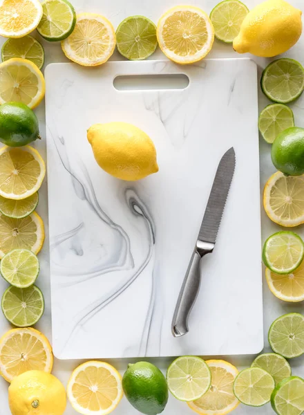 Above view of a cutting board surrounded by a border of fresh lemon and lime slices.