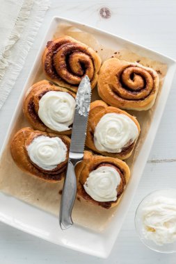 Bir tepsi tarçınlı çöreğin üstünde dört tane kremalı ve iki tane de kremalı..