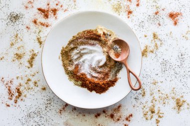 Karışık baharatlarla dolu bir tabak ve etrafa saçılmış bir sürü baharat..