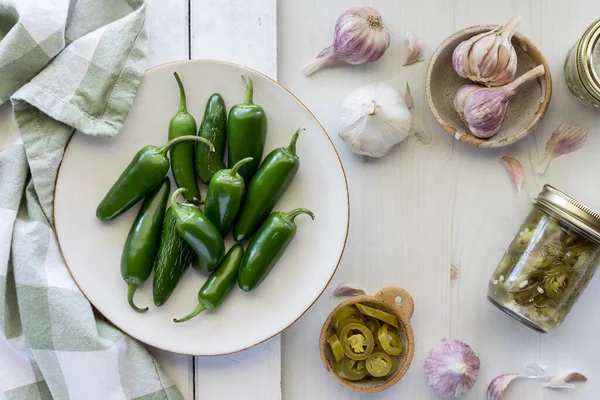 Taze jalapeno biberleri bir kavanoz ve bir kase dilimlenmiş jalapenolarla birlikte..