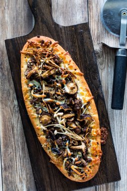 Fırından yeni çıkmış, dilimlenmeye hazır mantarlı biftekli pizzanın tepeden aşağı manzarası..