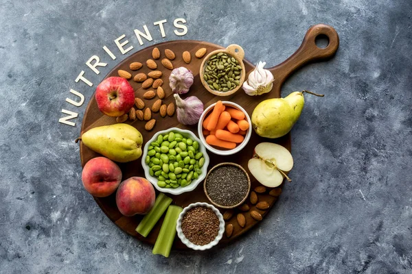 Top down view of an assortment of nutritious foods on a wooden board, against a blue background.