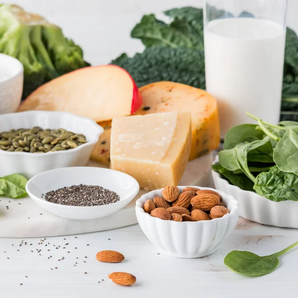 A close up of an assortment of calcium rich foods including greens and dairy.