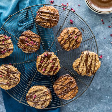 Çikolata serpilmiş ve gül yapraklarıyla serpilmiş serinletici rafta dantelli kurabiyeler..