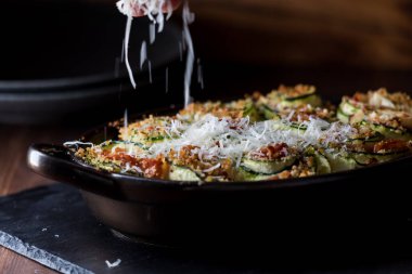 Yumuşak odaklı parmesan peyniri bir tabak kabağın üzerine serpilmiş, fırından yeni çıkmış..