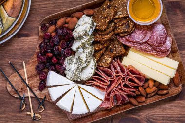 Top down view of a charcuterie board with various cheese, deli meat and crackers, for snacking. clipart