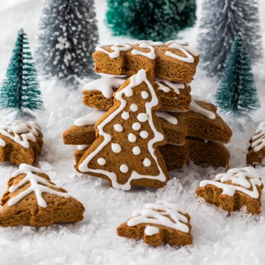 Arka planda ağaçlar ve her yerde kar olan şenlikli bir ağaç kurabiyesi düzenlemesi..