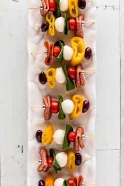 A long narrow platter of homemade antipasto skewers, ready for sharing. 