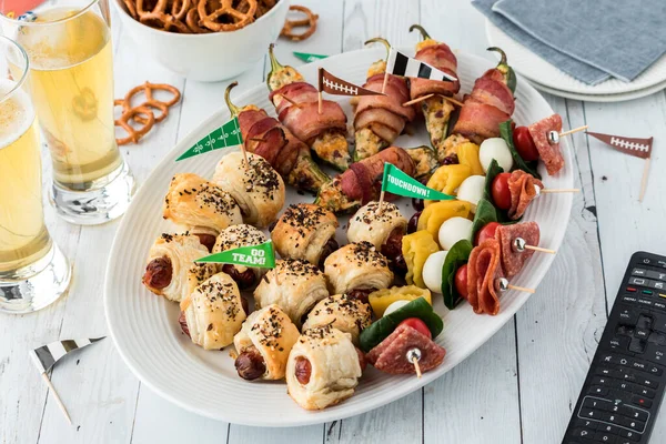 Close up of a platter full of game day appetizers served with beer, ready for watching the game on TV.