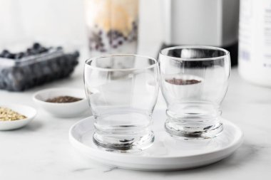 Arkasında protein yabanmersini püresi hazırlamak için kullanılan malzemeli boş bardaklar..