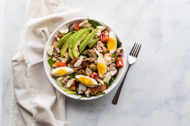 Avokado ve haşlanmış yumurta dilimli, yenmeye hazır sağlıklı bir tavuk salatası..