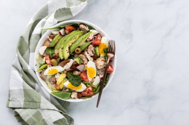 Haşlanmış yumurta, doğranmış tavuk ve dilimlenmiş avokado ile kaplanmış taze bir salata.. 