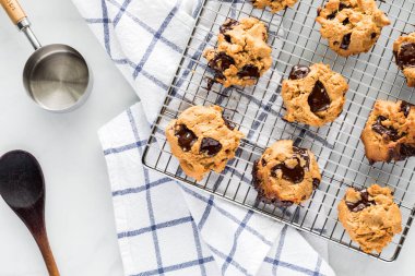 Fıstık ezmeli çikolatalı kurabiyeler serinletici rafta kareli havlunun üzerinde duruyor..