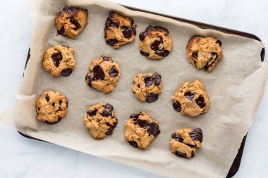 Fıstık ezmeli çikolatalı kurabiyeler parşömen kaplı kurabiye tepsisinde, fırından yeni çıkmış..