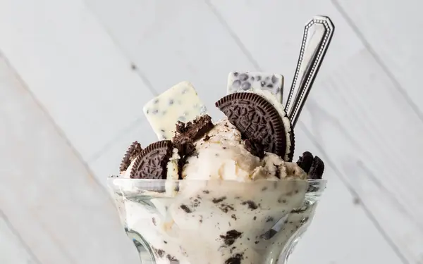 A close up of a cookies and cream ice cream dessert topped with chocolate pieces.