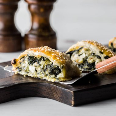 Tahta bir tahtanın üzerinde taze ıspanak ve feta hamur işlerini yakından izleyin.. 